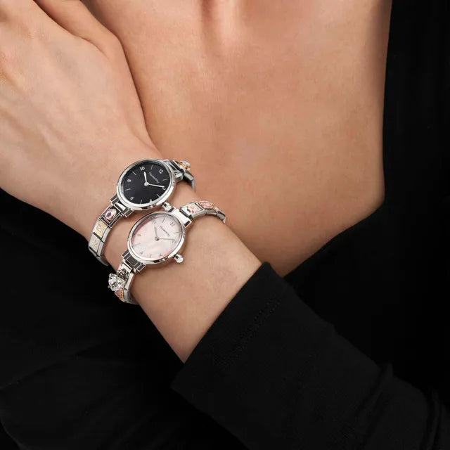 Two silver watches on a wrist against a black background