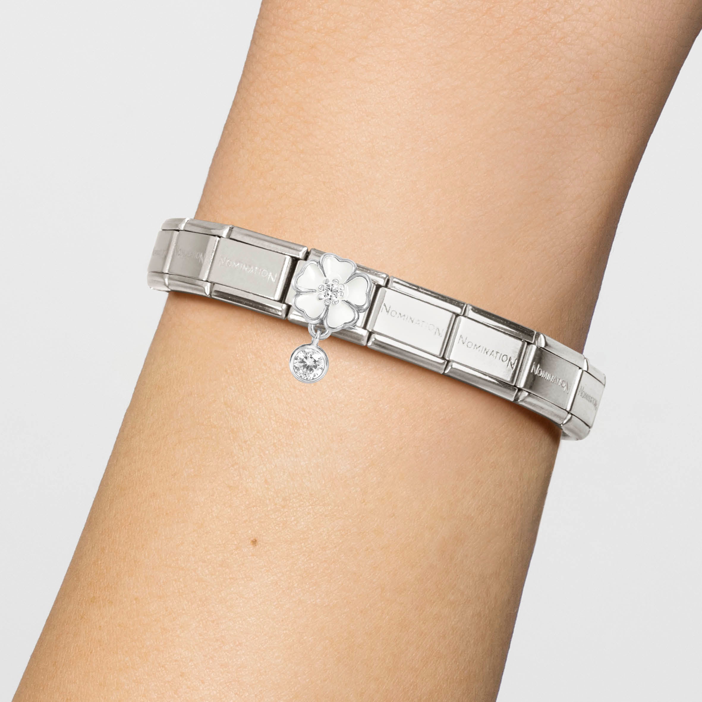 Silver charm with a white flower and clear gemstone on a white background