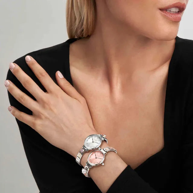 Woman wearing a silver watch on her wrist with a neutral background