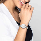 Person wearing a silver watch on a plain background