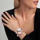 Woman wearing a silver watch on her wrist with a neutral background