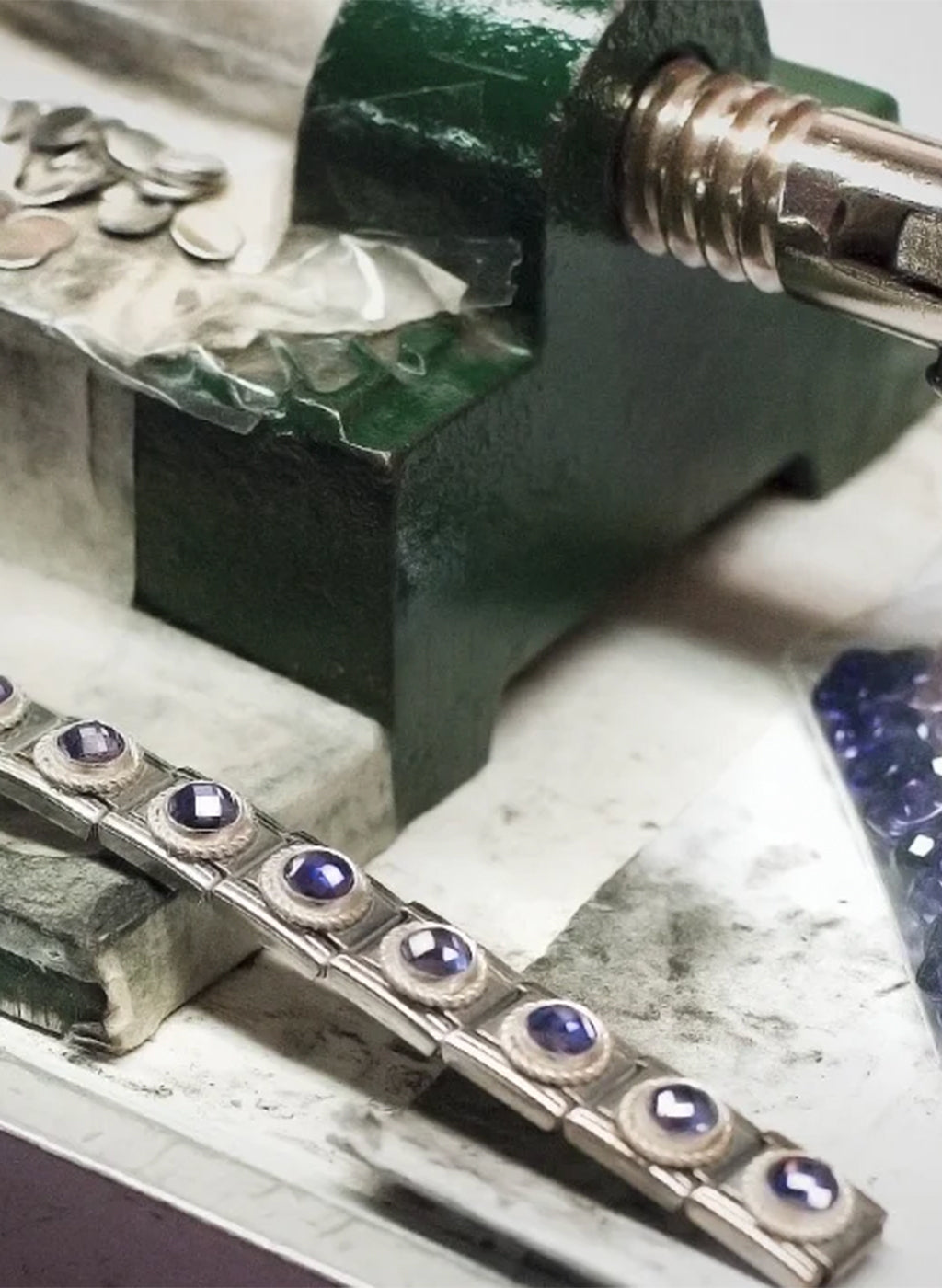 Jewelry piece with purple stones being worked on with tools