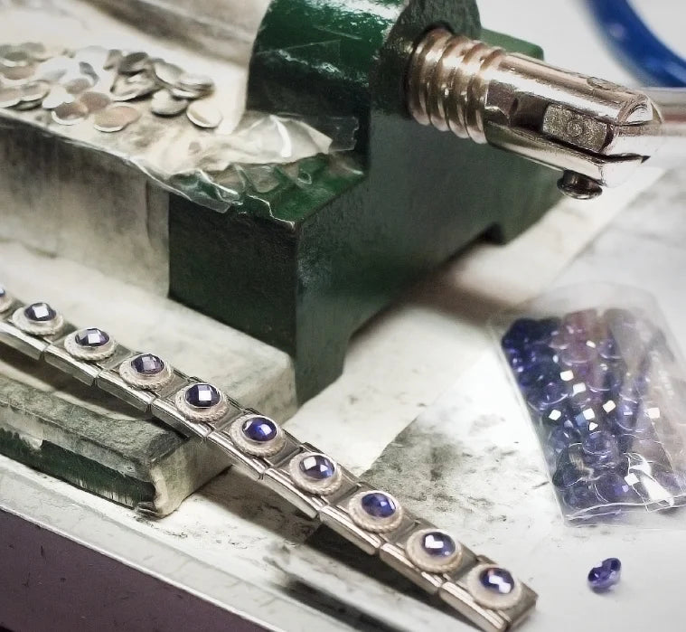 Jewelry-making process with gemstones and tools on a workbench